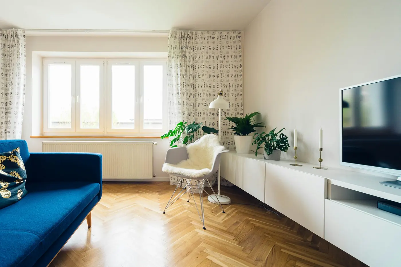Ventana blanca de PVC en un living con piso de madera y sofá azul.