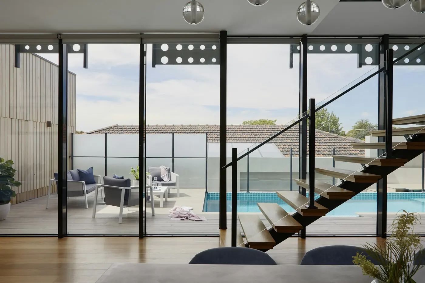 Ventanal corredero de gran formato abierto hacia una terraza con piscina.